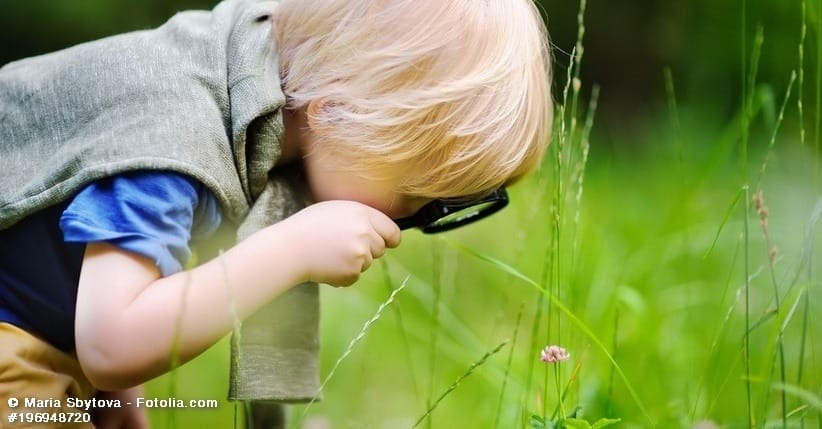 Kind das mit Lupe Blume betrachtet